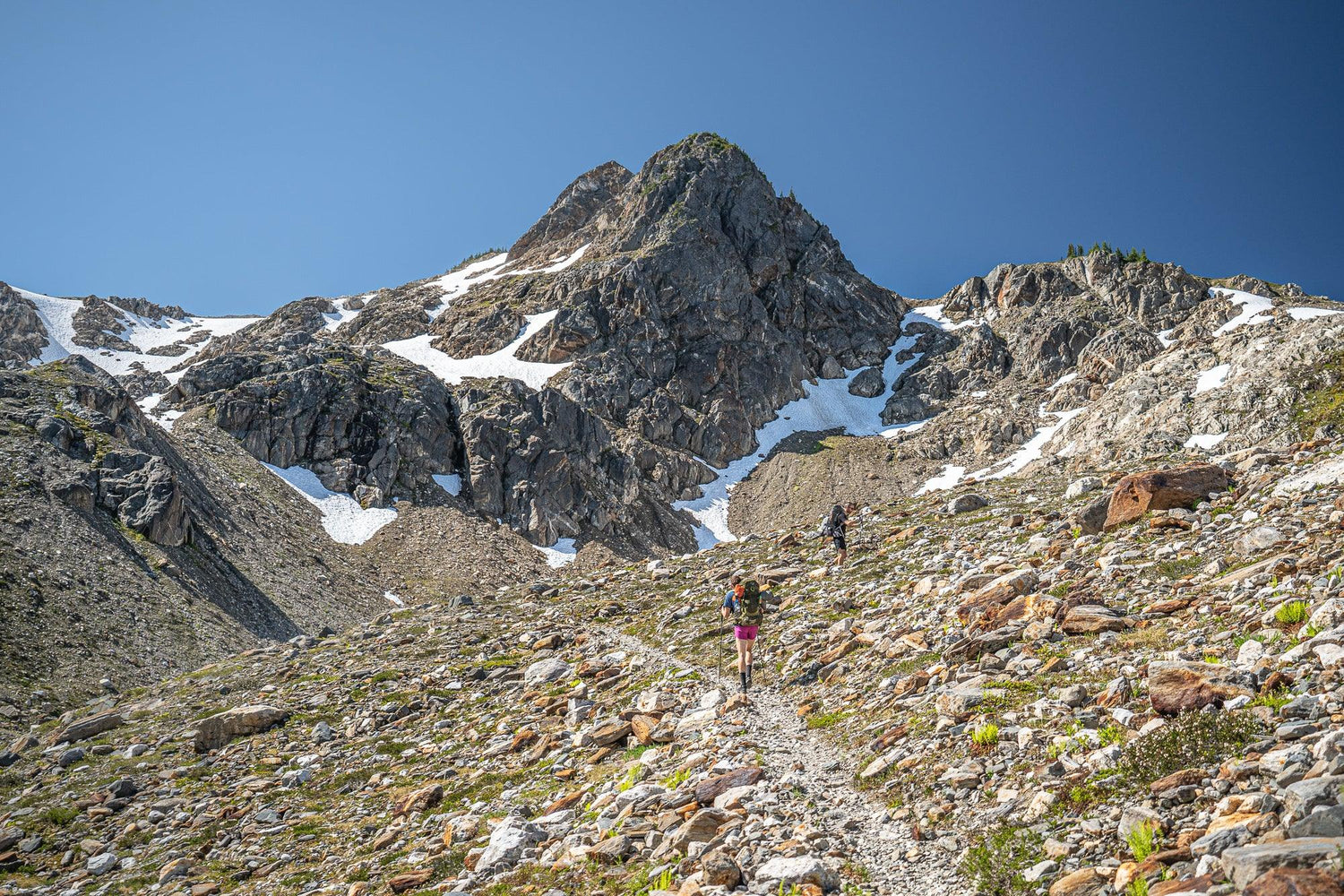 Fine Pacific Crest Trail photography print of a steep mountain pass south of Stehekin as two hikers climb to the top of the snow covered mountain.