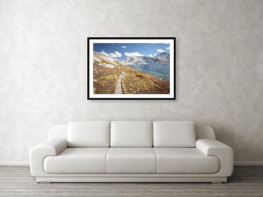 Framed fine photographic and wall art print of the Pacific Crest Trail meandering along a cold alpine lake in the High Sierra Mountain Range.