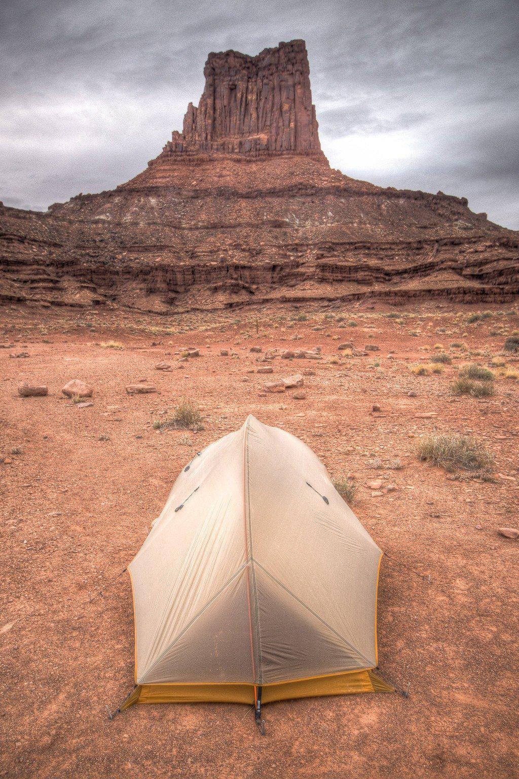 Fine photographic and art print of a small backpacker's tent in front of a red stone monument along Canyonlands National Park's White Rim Trail in Utah.