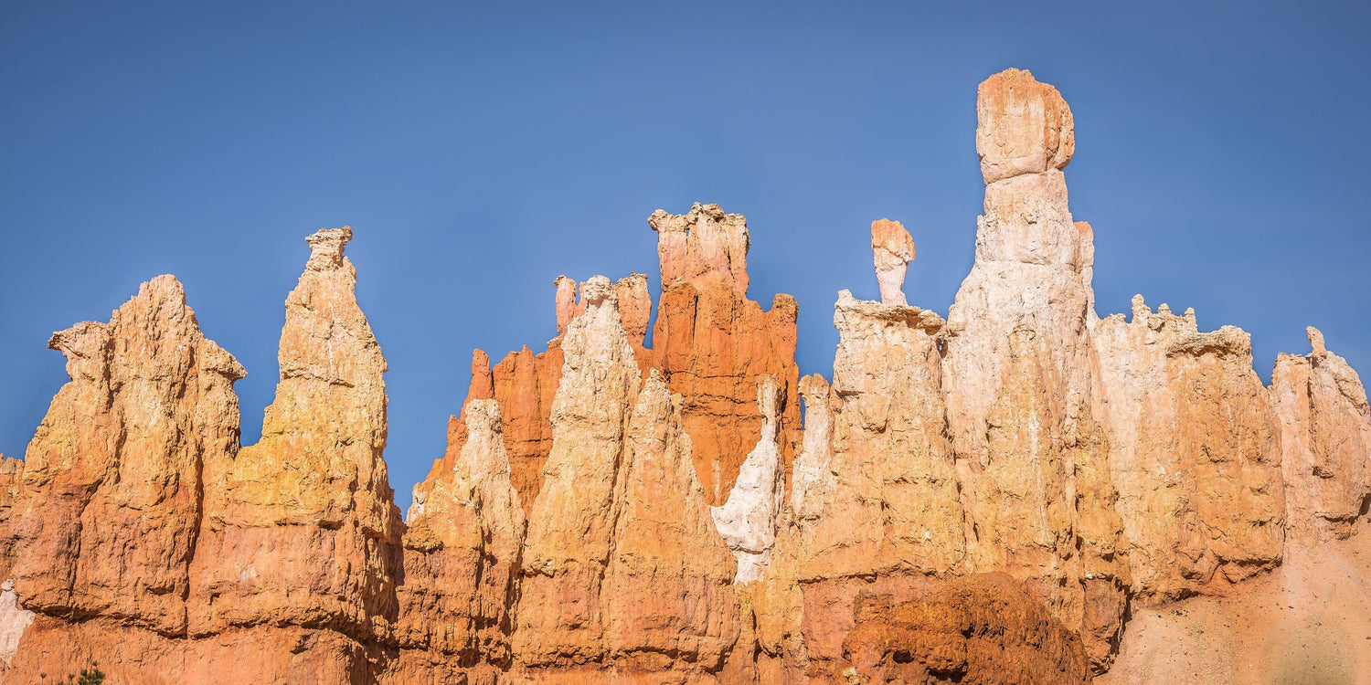 Fine Bryce Canyon National Park photography print of an array of orange and white hoodoo rock features against a blue sky backdrop.