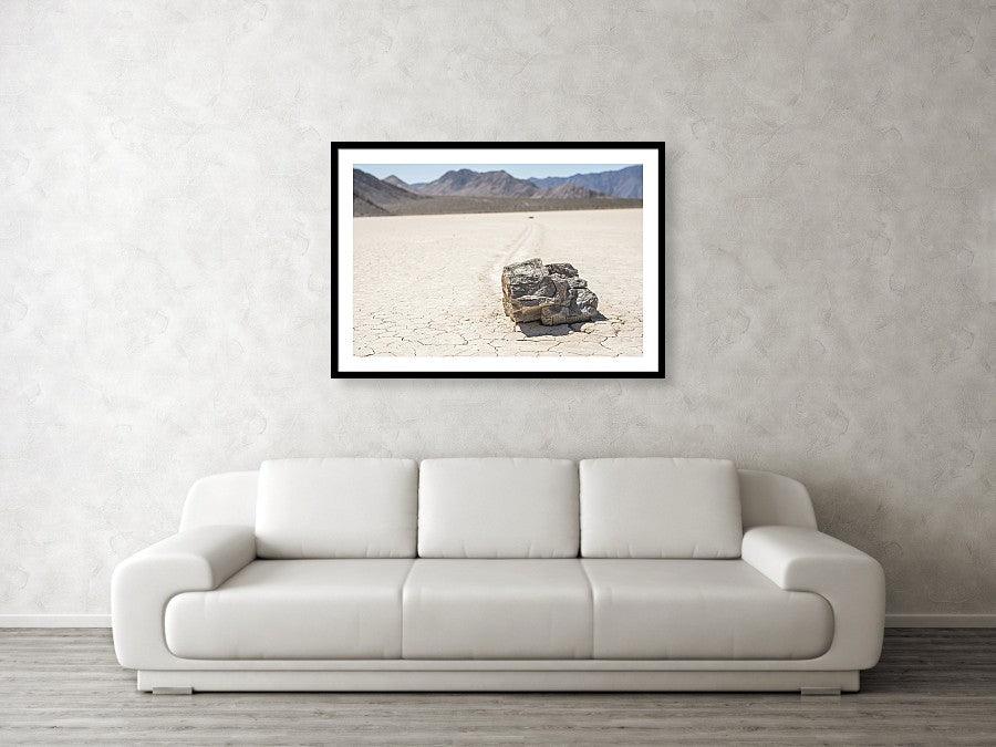 Framed fine photographic and wall art print of a single jagged rock carving a mysterious path through a cracked desert floor in Death Valley National Park in California.