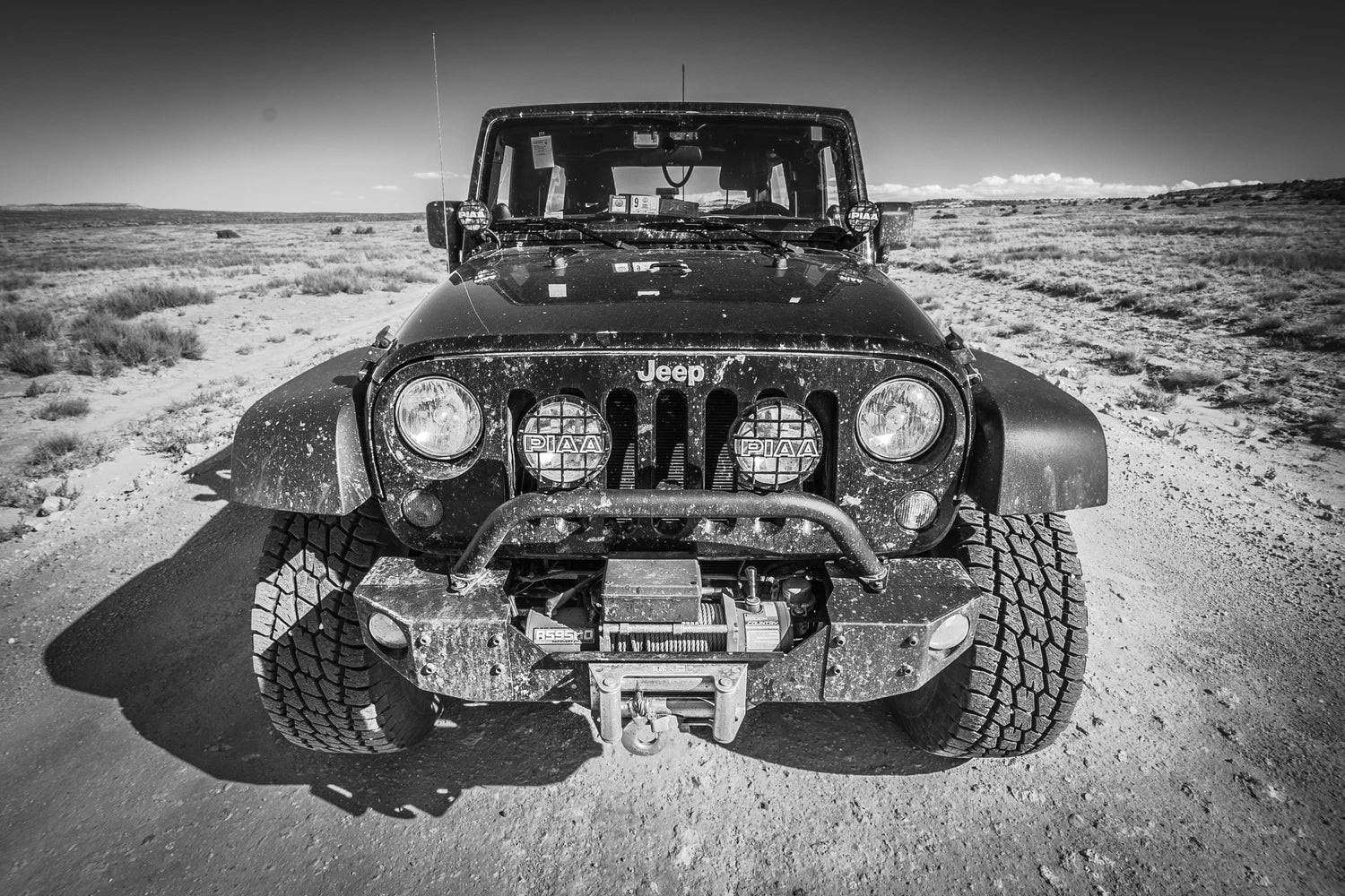 Fine black and white photographic and art print of a black Jeep Wrangler off-road driving along the White Rim Trail of Canyonlands National Park near Moab, Utah.