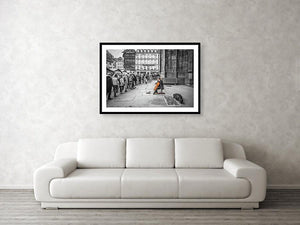 Framed fine black and white photographic and wall art print of a solo colorful cellist playing outside the doors of Strasbourg Cathedral as Christmas crowds gather and listen as they wait to enter.