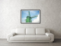 Framed fine photographic and wall art print of a single green windmill against a backdrop of blue dutch skies.