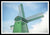 Framed fine photographic and art print of a single green windmill against a backdrop of blue dutch skies.